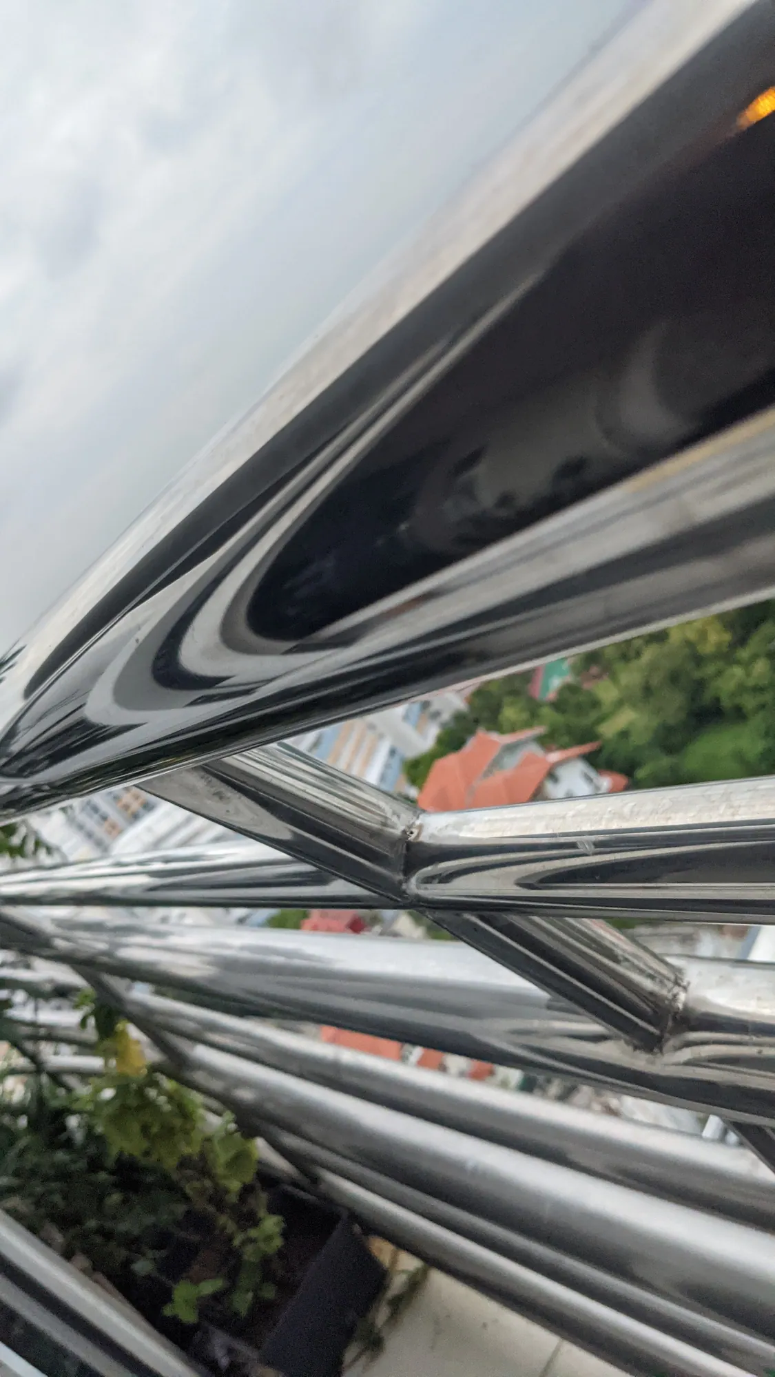 Polished metal railings bending reflections of sky and city