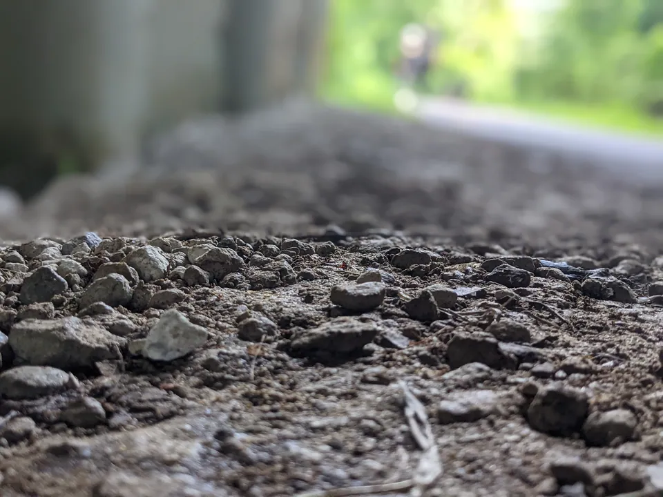 Gravel and dirt shot at ground level with a green path glowing in the distance