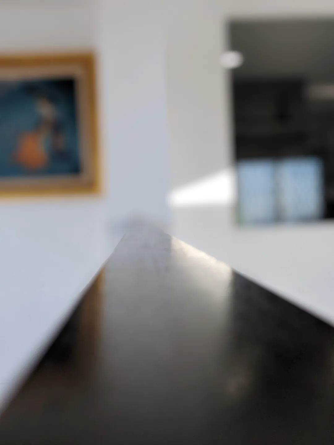 The dark edge of a tabletop cutting into a bright white room