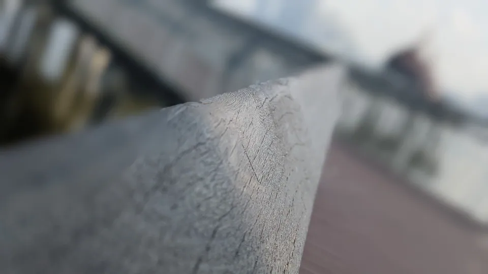 A worn wooden rail in sharp focus against a blurred boardwalk